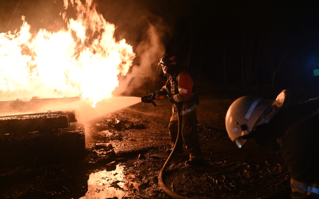 Ukrainian emergency personnel douse water to extinguish flames as they work at the site of a drone attack in Kharkiv, early on February 10, 2024. Seven people, including three children, were killed Saturday in a Russian drone attack on the city of Kharkiv in eastern Ukraine, the regional governor said. "Unfortunately the death toll from the occupiers' attacks on Kharkiv has risen to seven," Oleg Synegubov said on the Telegram social network. "Among them are three children: 7, 4 years old and a baby about six months old." (Photo by SERGEY BOBOK / AFP)