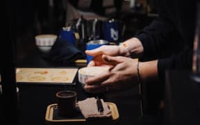 A person holds a latte they have prepared.