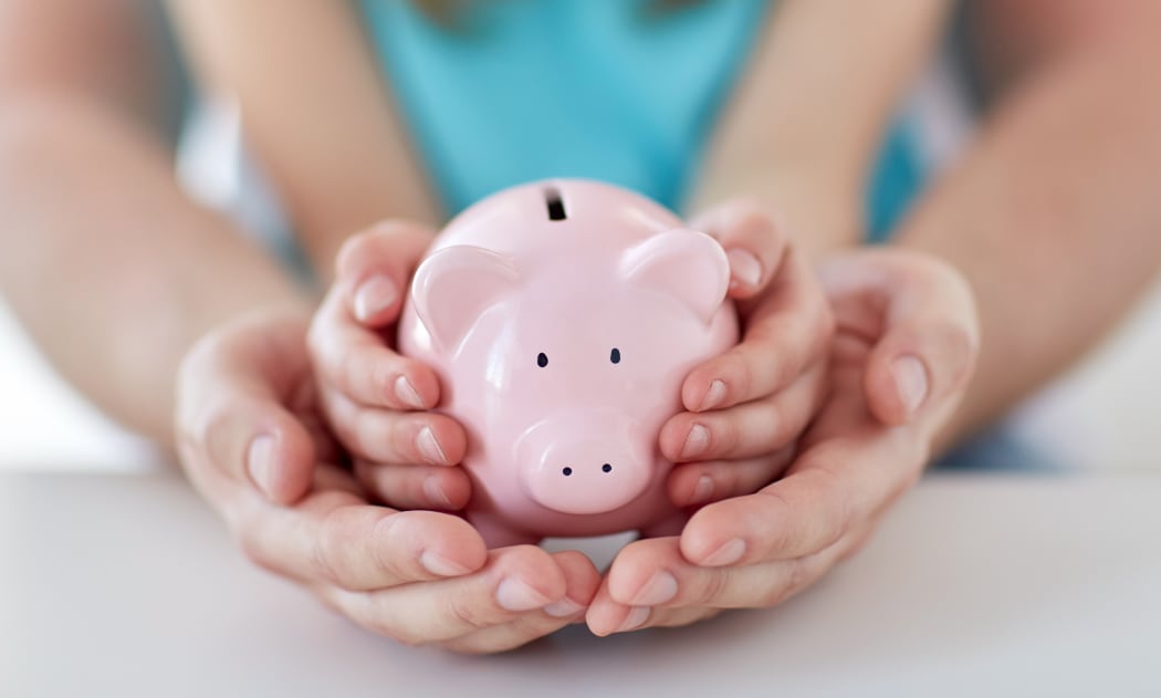 A man and a child hold a piggy bank