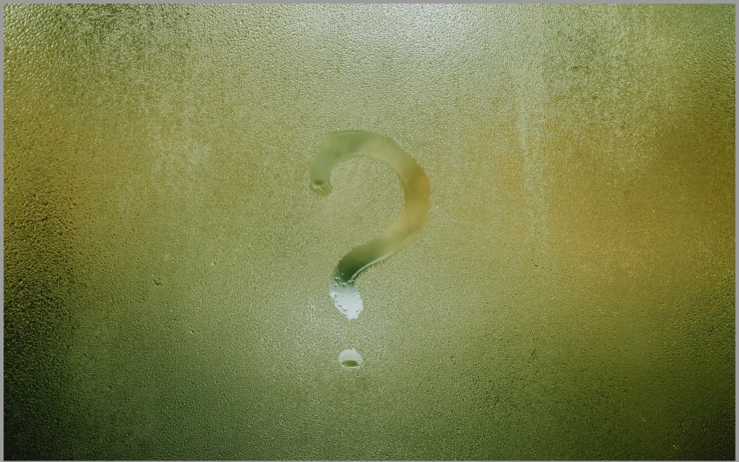A question mark written into condensation on a window.