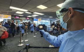 This handout picture released by the Panamanian Health Ministry shows health workers checking the temperature of passengers at Tocumen International Airport, in Panma City on March 13 2020.