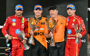 (From L) Ferrari's Spanish driver Carlos Sainz Jr., McLaren's British driver Lando Norris, McLaren's US principal Zak Brown and Ferrari's Monegasque driver Charles Leclerc celebrate on the podium after the Abu Dhabi Formula One Grand Prix,  2024.