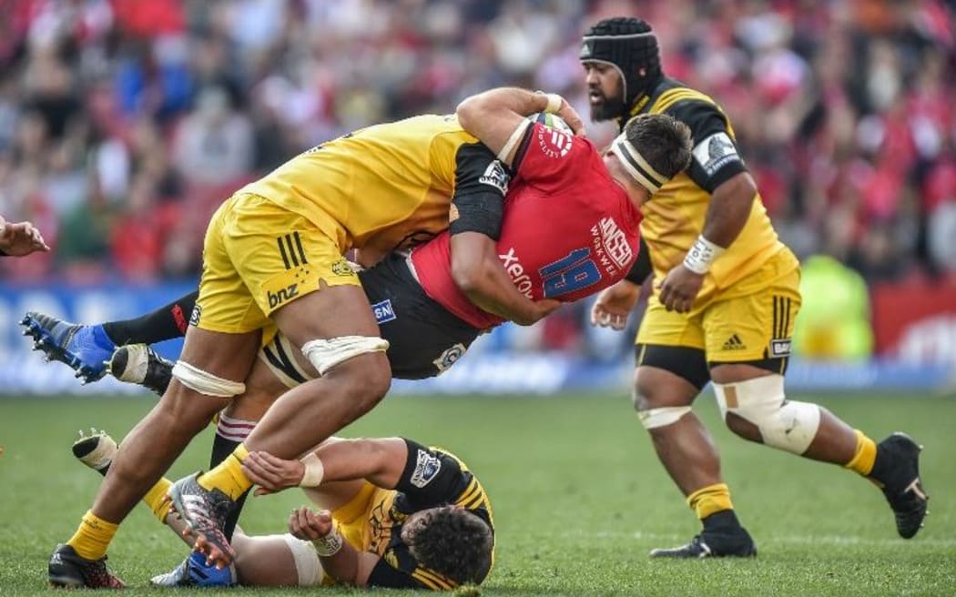 Sam Lousi, left, of the Hurricanes tackles Lourens Erasmus of the Lions during the Super Rugby semi-final match.