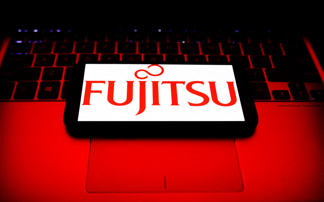 Fujitsu logo displayed on a phone screen and a laptop keyboard are seen in this illustration on October 30, 2021.