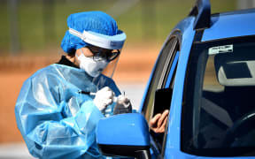 A health worker takes a swab sample at a Covid-19 coronavirus drive through testing site in the Smithfield suburb of Sydney on August 12, 2021.