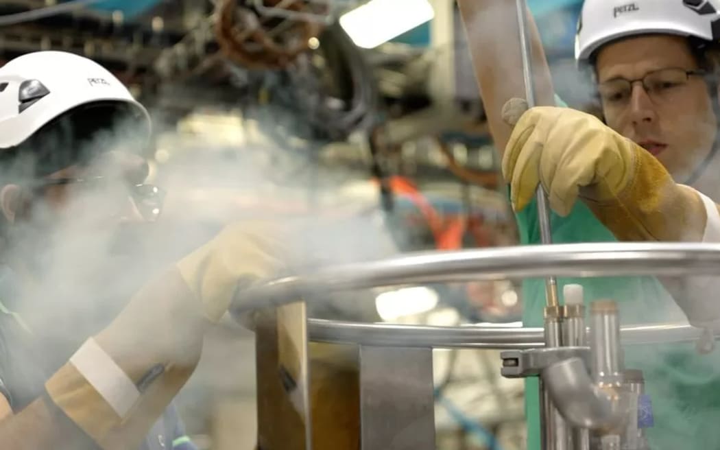 Engineers adding liquid helium to the system to keep antimatter at minus 270 celcius, near to the lowest possible temperature, absolute zero
