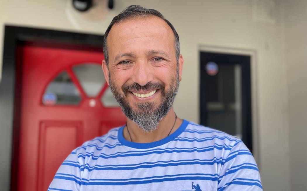 Temel Atacocugu standing outside his front door, which he has painted red to honour his Turkish heritage.