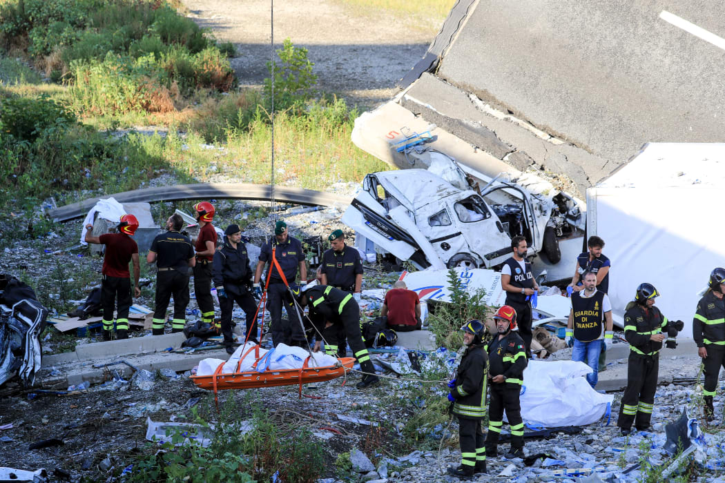 Rescuers and security forces evacuate a body at the site where the Morandi motorway bridge collapsed in Genoa