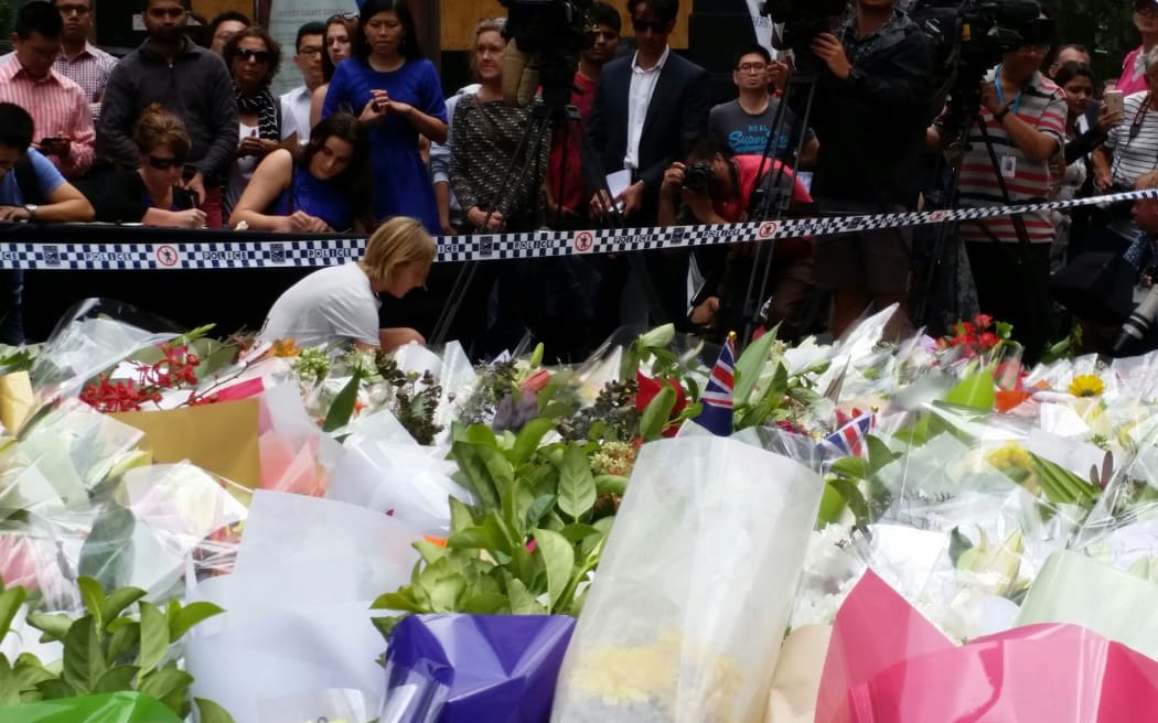 A woman adds her tribute to a sea of flowers in Sydney Martin Place.