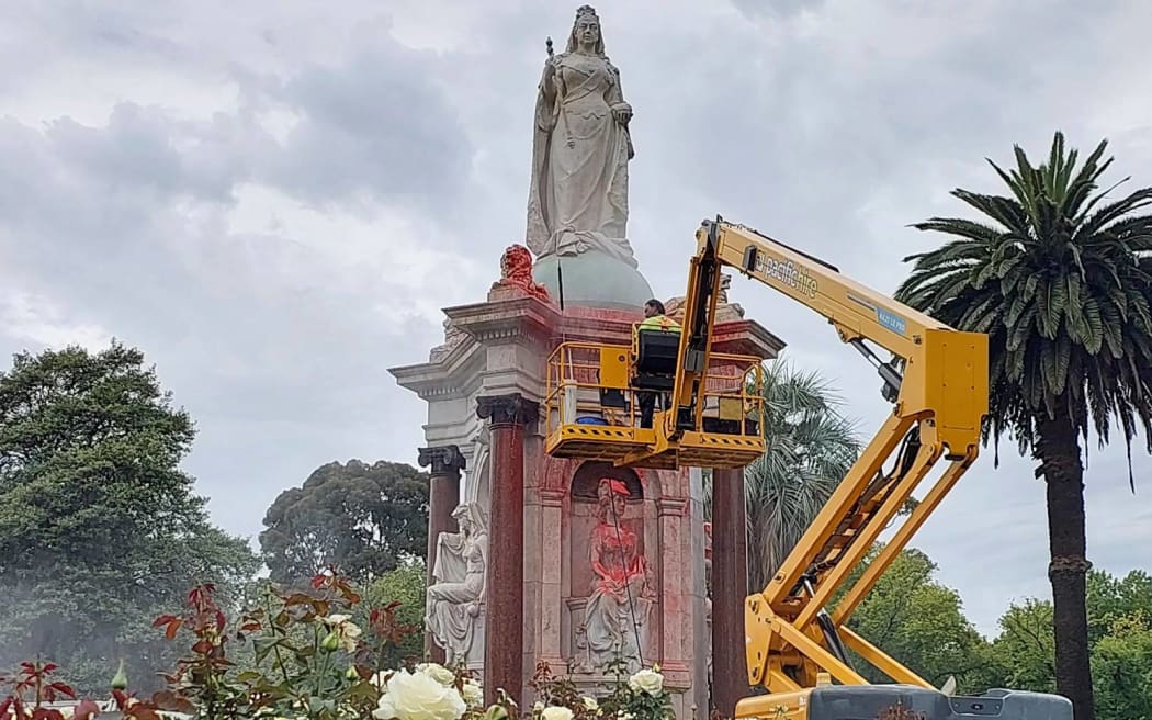 A council worker cleans the statue to Britain's Queen Victoria that was defaced in the Royal Botanic Gardens Victoria in Melbourne on January 25, 2024, ahead of Australia Day. (Photo by Martin PARRY / AFP)