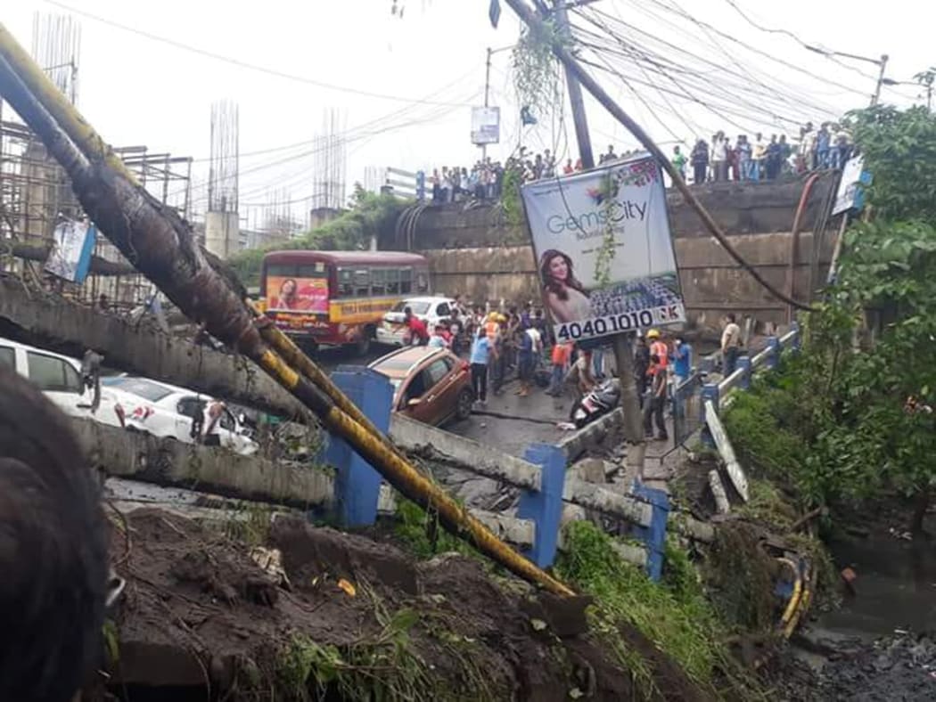 Indian rescue teams and onlookers stand on rubble and atop Majerhat bridge after a segment of the bridge suddenty collapsed in Kolkata in the Indian state of West Bengal.
