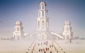 A large structure rises out of the desert.