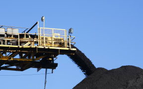 Conveyor belt carrying coal and pouring onto a pile
