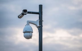 A security camera, pointed down from a tall pole.