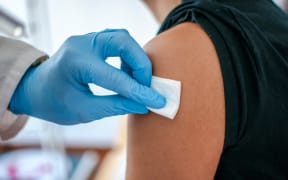 Doctor disinfects skin of patient before vaccination.