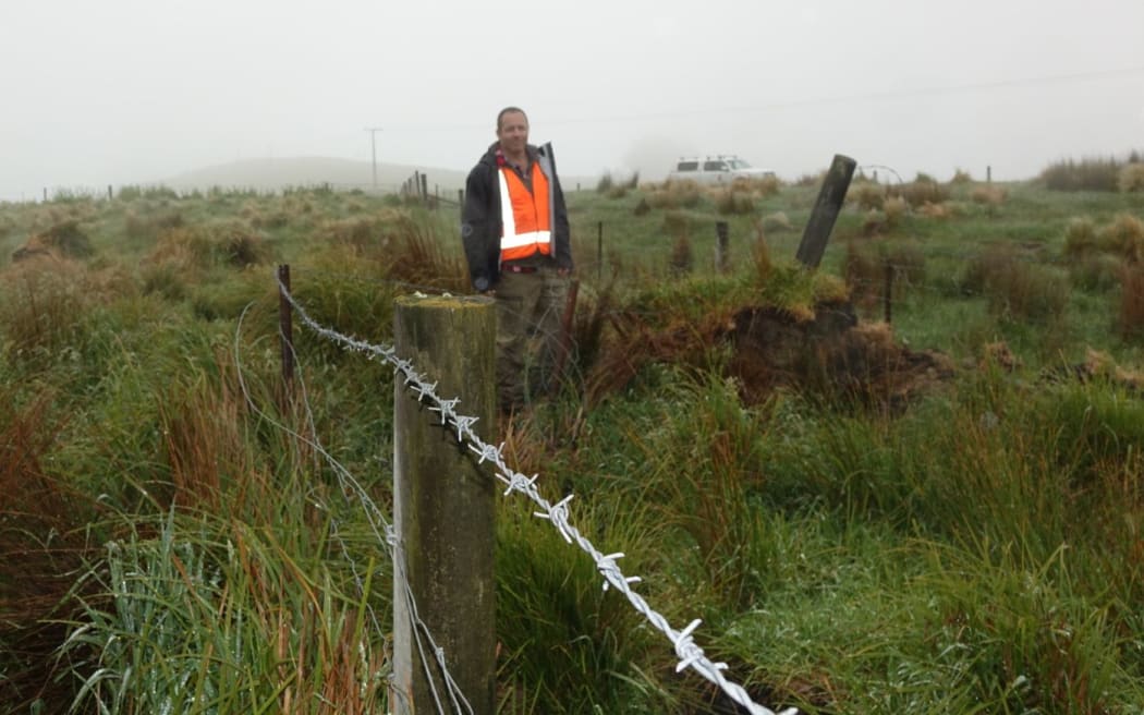 Adrian Benson stands beside a fence that was once straight.