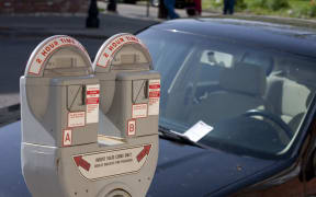6998921 - parking meter with a car in the background with a ticket on the windshield