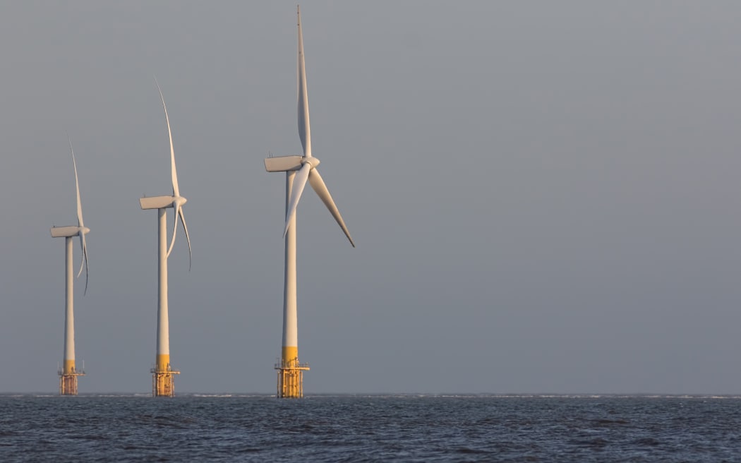 Offshore wind turbines. Wind farm on the sea horizon. Clean energy. Profile of three massive sustainable resource power generation turbines.