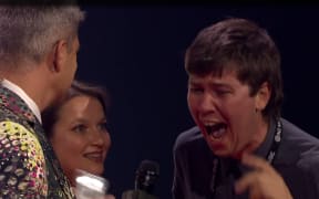 Callum Devlin (right) of Filmmaking duo Sports Team shouts into a microphone held by Aotearoa Music Award host Jesse Mulligan, with Annabel Kean (centre).