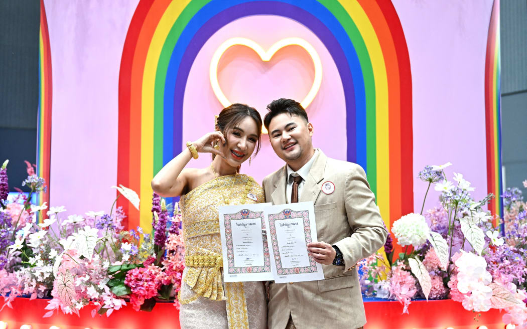Kevin Pethai Thanomket (left) and Maple pose for pictures after registering their same-sex marriage in Bangkok on 23 January, 2025, as scores of same-sex and transgender couples married in Thailand on January 23 as the kingdom's equal married following a law change.