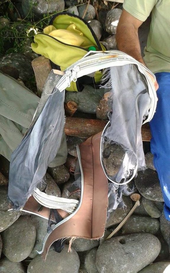 A local shore cleaner on the Indian Ocean island of La Reunion, with the remains of a suitcase that could be from the missing flight MH370.