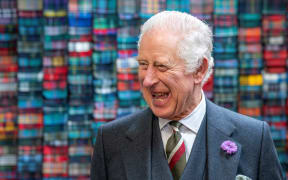 King Charles III laughs during a visit to the Lochcarron of Scotland tartan weaving mill in Selkirk, south of Edinburgh, on 6 July, 2023.