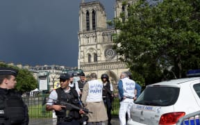 French police officials and investigators gather near the entrance of Notre Dame cathedral in Paris after police shot and injured a man who had tried to attack an officer with a hammer.