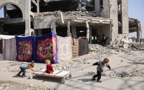 Displaced Palestinian children play outside the damaged Imam al Shafi’i Mosque, where their families have taken shelter, in the Zeitoun neighbourhood of Gaza City on October 23, 2025. (Photo by Omar AL-QATTAA / AFP)