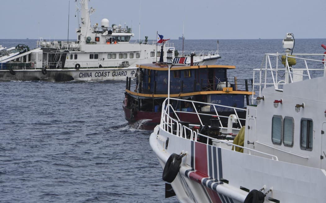Chinese coast guard ships (left and right) corral a Philippine civilian boat chartered by the Philippine navy to deliver supplies to Philippine navy ship BRP Sierra Madre in the disputed South China Sea, on 22 August.