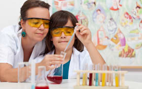 A file photo shows a primary school student being helped by a teacher in a school chemistry lab.
