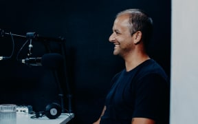 Journalist Justin Latif sitting in front of a microphone