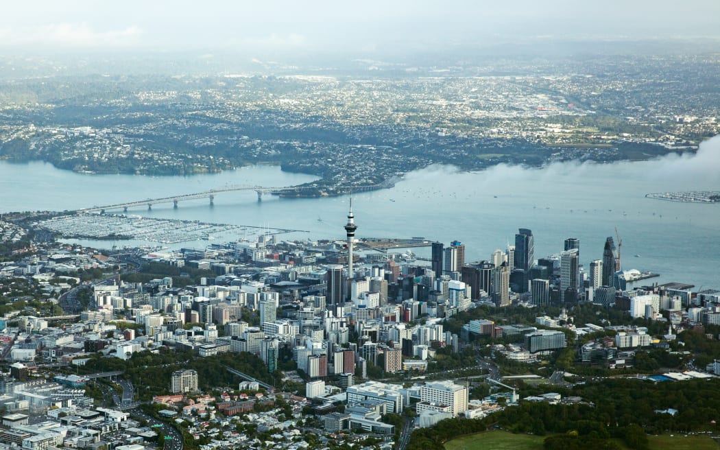 An aerial view of Auckland city, showing both the Harbour Bridge and the Sky Tower.