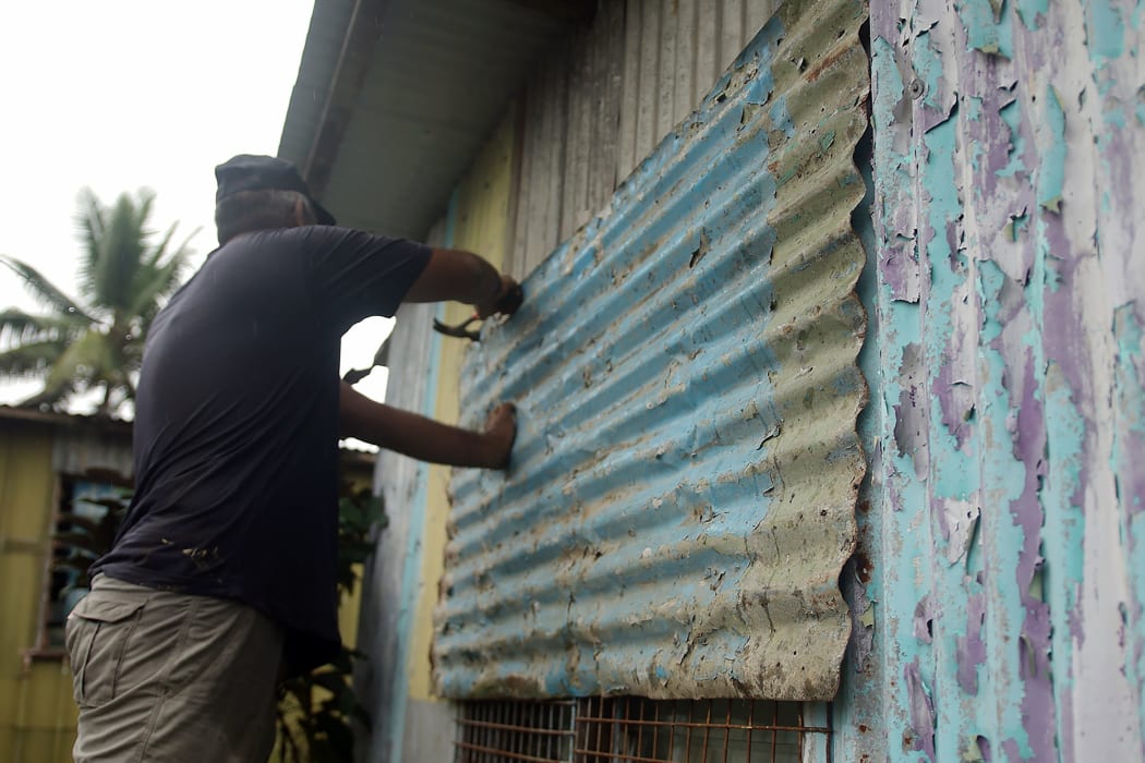 A resident placing corrugated iron on the window of his house in Fiji's capital city of Suva on December 16, 2020, ahead of super Cyclone Yasa.