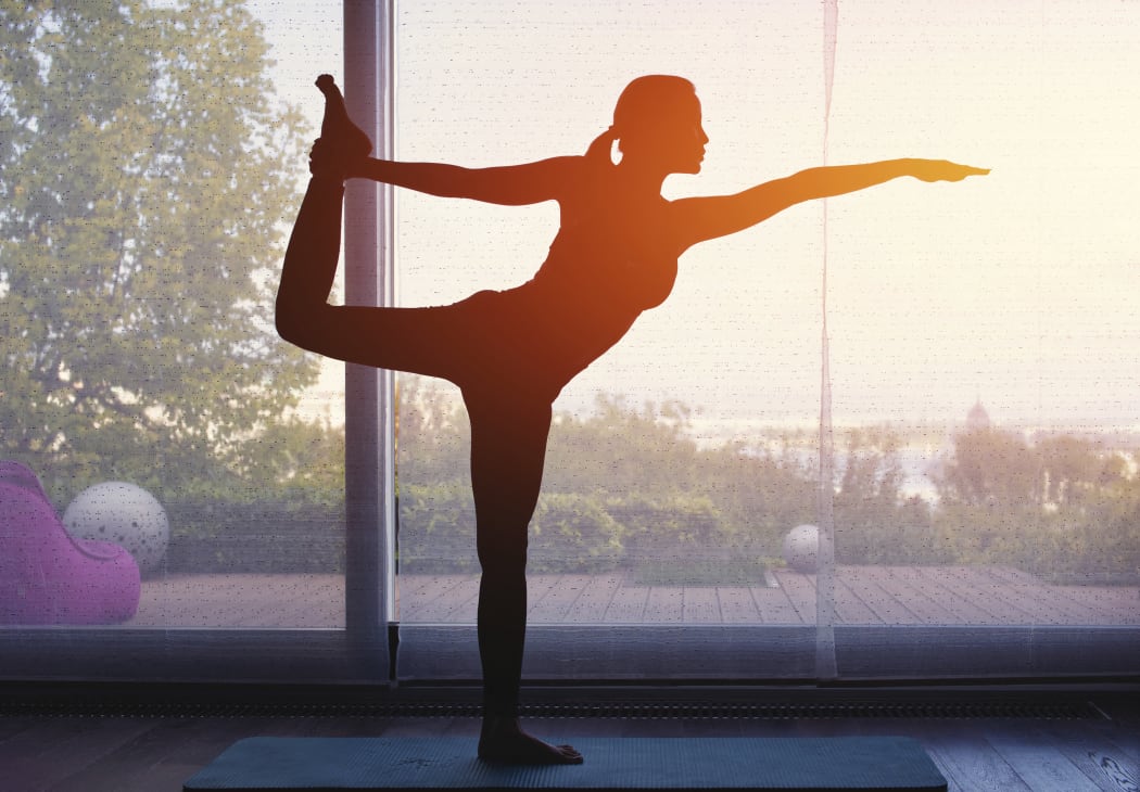 Silhouette of woman doing yoga at home at sunset. (Science Photo Library via AFP)
