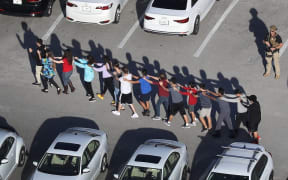 People are brought out of the Marjory Stoneman Douglas High School after a shooting at the school.