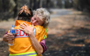 This photo taken on January 8, 2020 shows 64-year-old orchardist Stephenie Bailey (R) reacting as she describes the impact bushfires have had on her farm in Batlow, in Australia's New South Wales state.