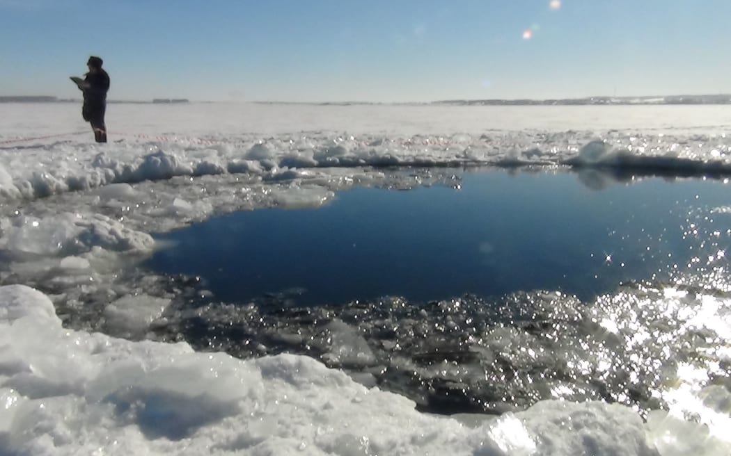 A police officer stands near a six-metre hole in the ice of a frozen lake, reportedly the site of part of the meteorite that exploded over Chelyabinsk in Russia.