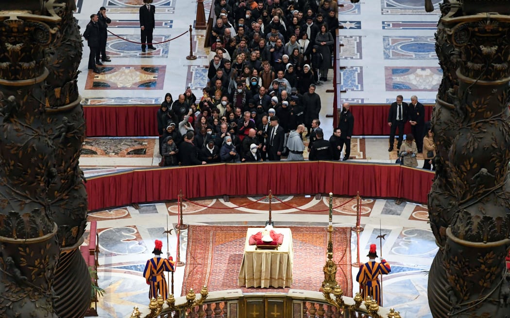 This handout picture taken and released on January 2, 2023 by the Vatican media shows people waiting in line to pay their respect at the body of Pope Emeritus Benedict XVI laying in state at St. Peter's Basilica in the Vatican. - Benedict, a conservative intellectual who in 2013 became the first pontiff in six centuries to resign, died on December 31, 2022, at the age of 95. Thousands of Catholics began paying their respects on January 2, 2023 to former pope Benedict XVI at St Peter's Basilica at the Vatican, at the start of three days of lying-in-state before his funeral.