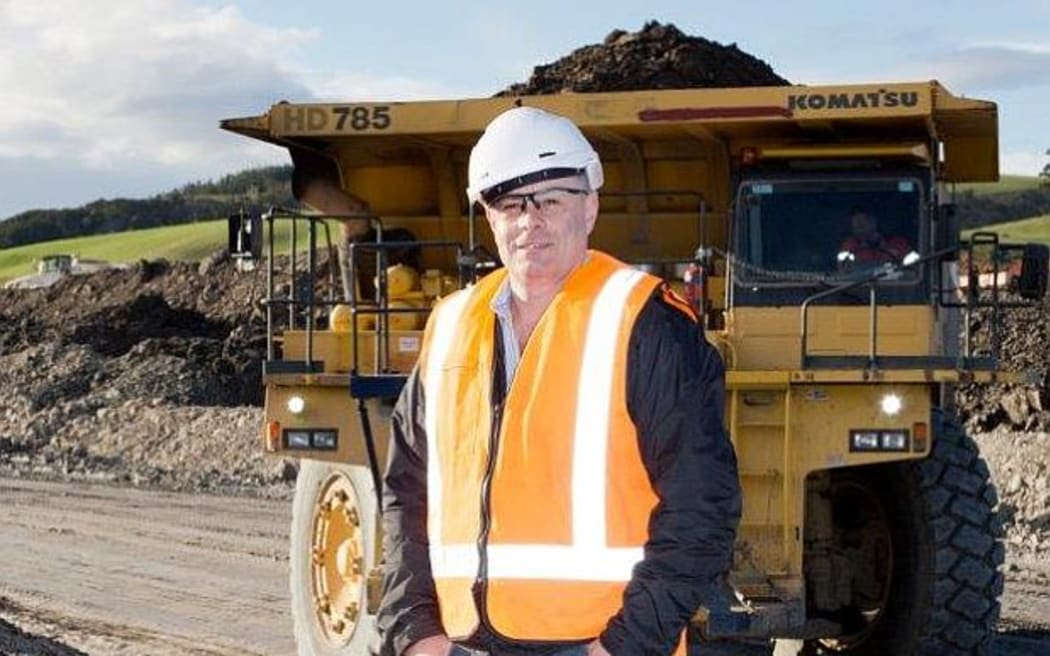 Bathurst Chief Executive stands in hard hat and gumboots near heavy truck and coal.