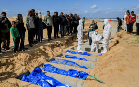 The bodies of Palestinians killed during the war are buried in a mass grave on January 30, 2024 in Rafah, Gaza. The health ministry in Gaza said 80 bodies and 20 remains of bodies heavily decomposed confiscated by Israeli forces were handed over through the Israeli-controlled Kerem Shalom crossing and were buried in mass graves in the city of Rafah in the south of the Gaza Strip. (Photo by Yasser Qudihe / Middle East Images / Middle East Images via AFP)