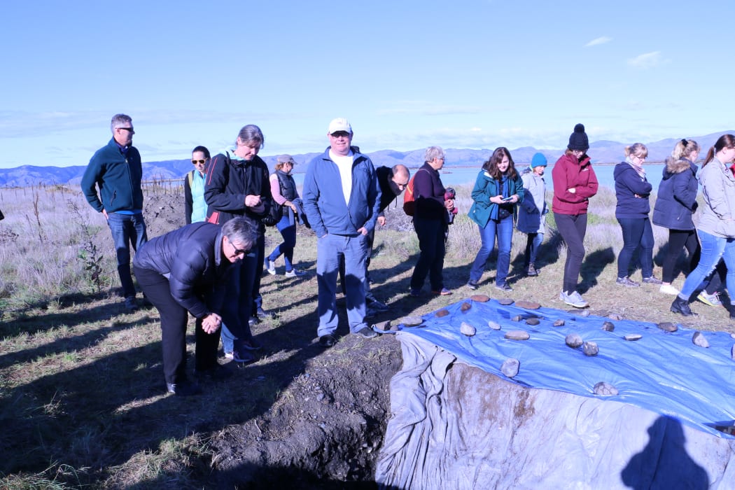 A group of iwi members and archaeologists visits one of six large, ceremonial hangi pits that have been uncovered at Wairau Bar.