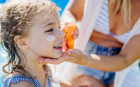 A child getting sunscreen applied to their face.