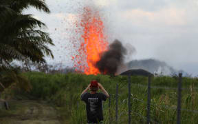 A man takes a photo of a lava fountain from a Kilauea volcano fissure on Hawaii's Big Island