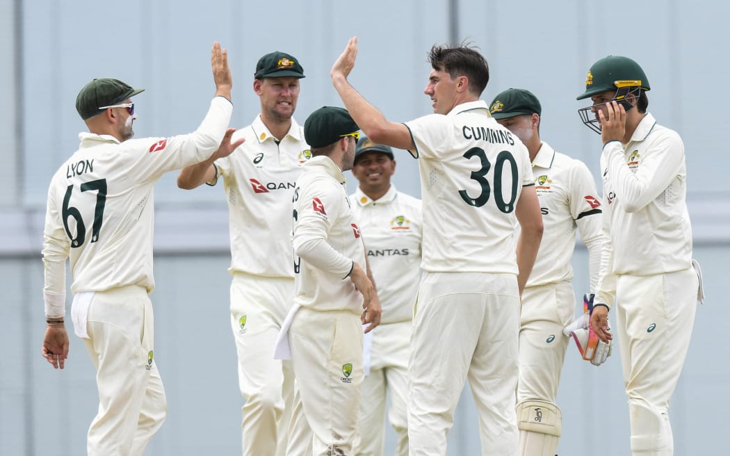 Pat Cummins (2R) and Nathan Lyon (L) of Australia celebrate the dismissal of Roston Chase of West Indies during the 2nd day of the 1st Test match between West Indies and Australia at Kensington Oval, Bridgetown, Barbados, on June 26, 2025. (Photo by Randy Brooks / AFP)