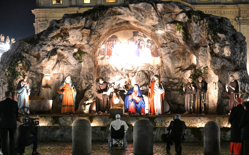 Pope Francis (centre, in wheelchair) poses in front of a Nativity Scene on Saint Peter's Square in The Vatican on 31 December, 2023.