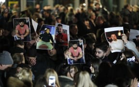 Mourners hold up photos, believed to be of vicitims, during a vigil close to a crime scene in Hanau, near Frankfurt.
