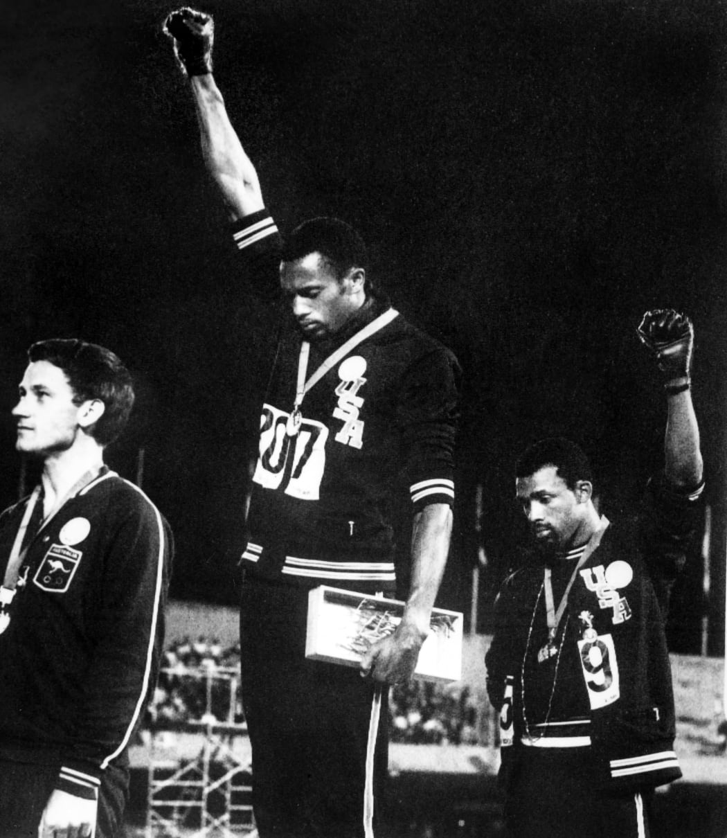 Tommie Smith (centre) and John Carlos (right) raise gloved fists in the Black Power salute to express their opposition to racism in the US after receiving medals for first and third place in the men's 200m at the 1968 Mexico Olympic. At left is Australian Peter Norman.