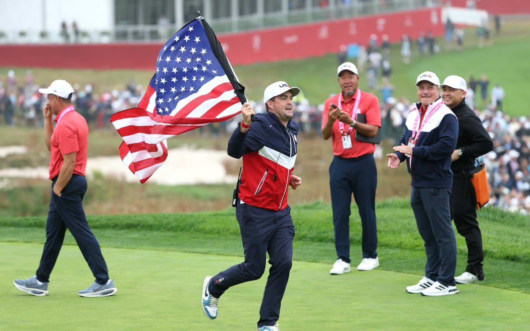 Captain Keegan Bradley of Team United States runs the 18th hole with an American flag during a practice round prior to the Ryder Cup 2025 at Black Course at Bethpage State Park Golf Course, New York.