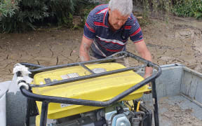 Keith Gore's brother, Errol, starts the generator to begin waterblasting silt.