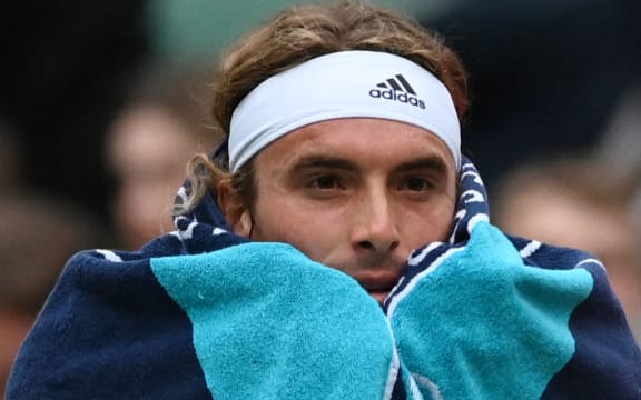 Greece's Stefanos Tsitsipas wraps himself in a towel during a pause in his men's singles tennis match against Australia's Nick Kyrgios on the sixth day of the 2022 Wimbledon Championships at The All England Tennis Club in Wimbledon, southwest London, on July 2, 2022. (Photo by Glyn KIRK / AFP) / RESTRICTED TO EDITORIAL USE